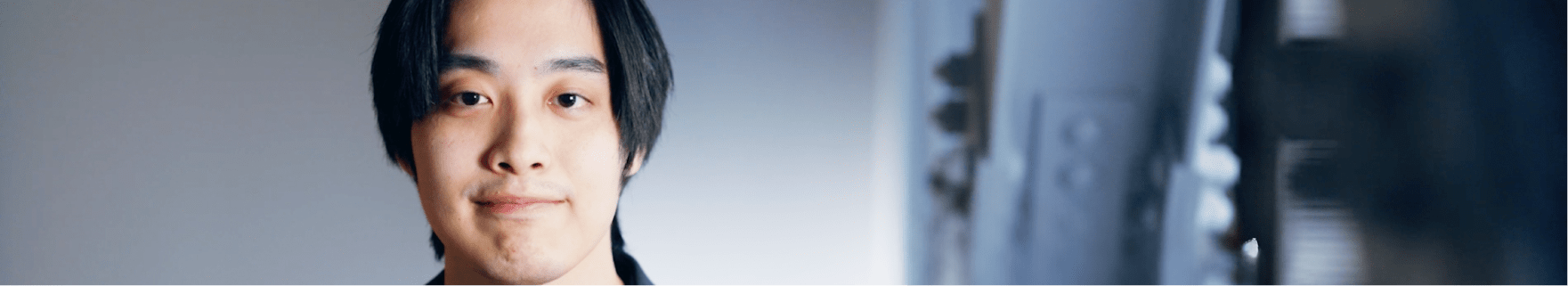 若い男性社員がカメラに向かって穏やかに微笑んでいる写真